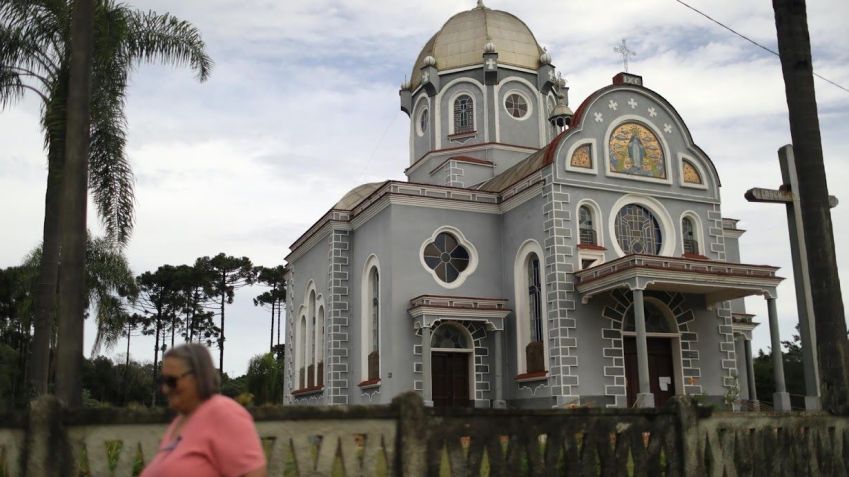 Mulher caminha em frente a uma igreja em Prudentópolis/ Pilar Olivares/Reuters (25.fev.2022)