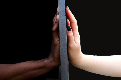Duas mãos. Uma é de uma pessoa negra e a outra de uma pessoa branca